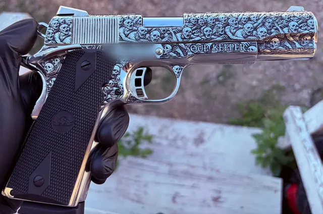 Side profile of a pistol with full relief skull motif engraving