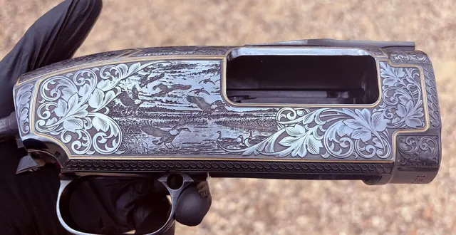 Engraved receiver with a waterfowl relief scene and gold inlay lines