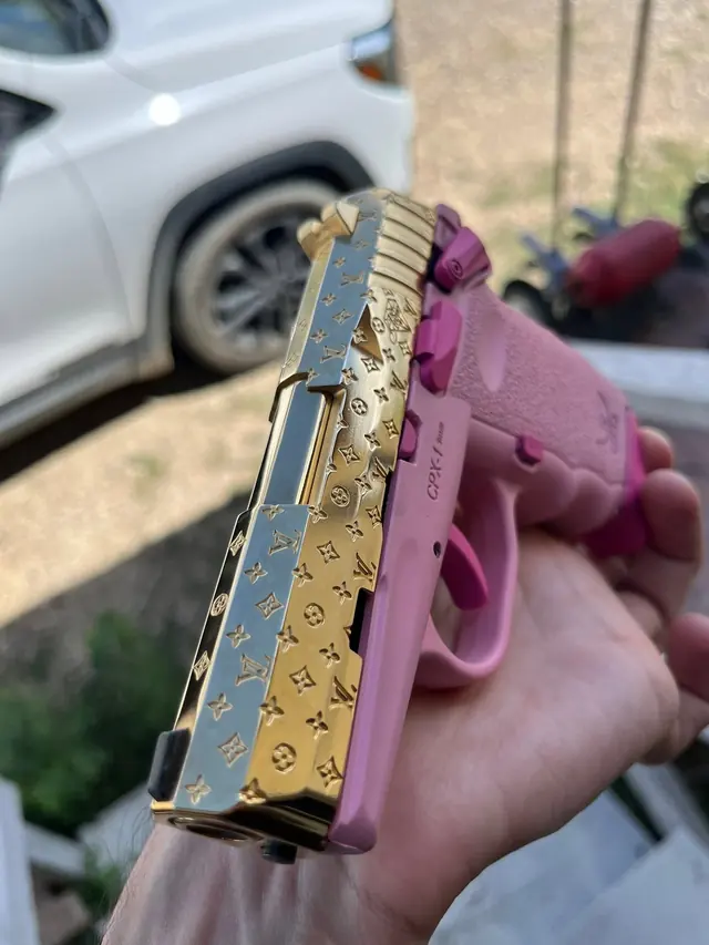 Pistol slide engraved with a custom monogram pattern in gold finish